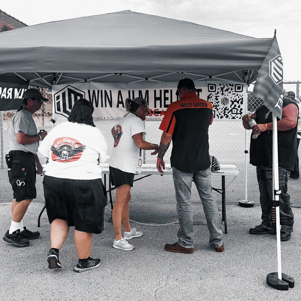 people standing around the ILM helmet booth at Big River Rally to sign up to win